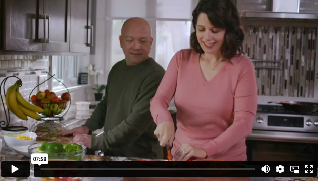 Ann smiling while chopping vegetables in the kitchen, with a companion nearby, Somatuline® Depot patient story.